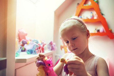 Little child playing with figurines in bedroom