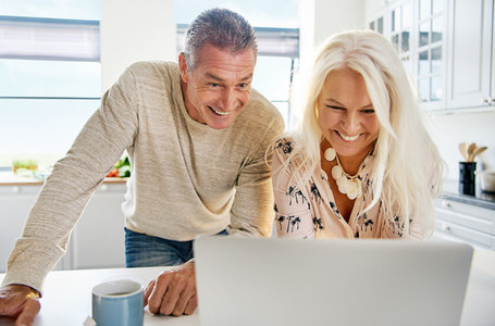 Laughing middle aged couple looking at computer