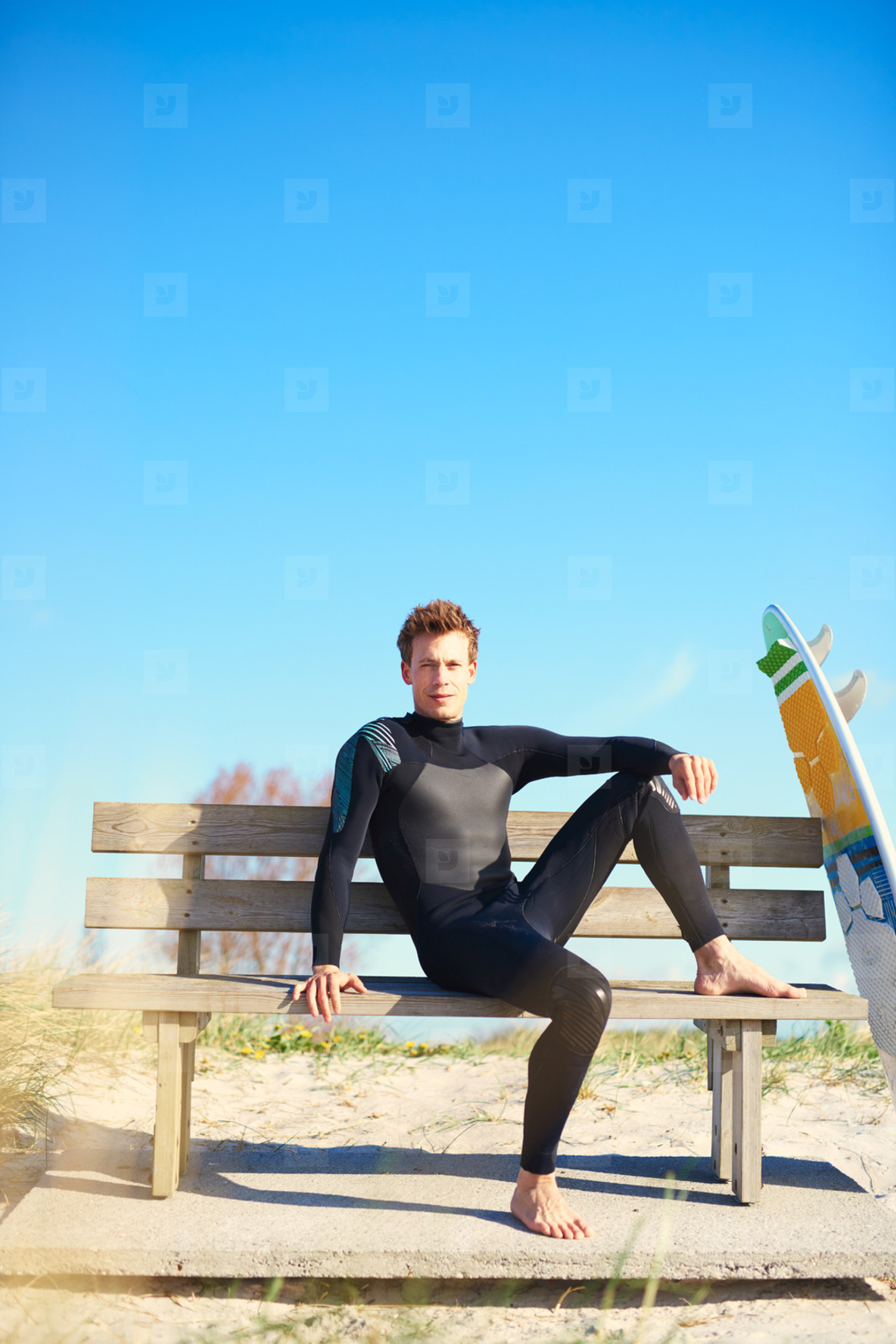Relaxed surfer waiting on a wooden bench