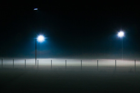 Lonely and mystic football field covered by fog at night