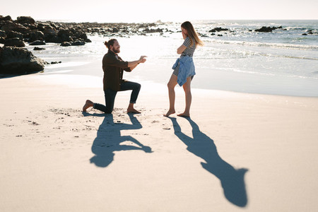 Man kneeling and proposing to woman by the sea