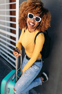 Cheerful woman traveller in sunglasses with a trolley bag