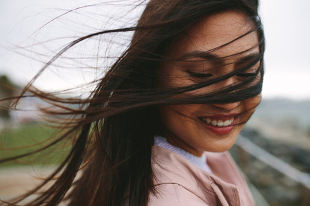 Close up of a smiling woman with her hair flying on her face