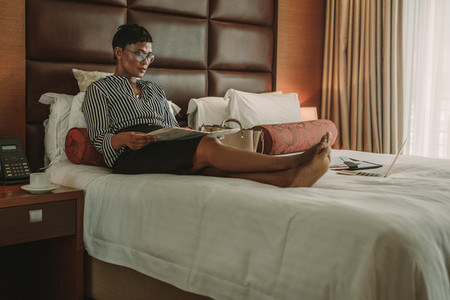 Businesswoman reading a newspaper in modern hotel room