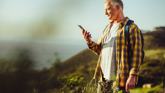 Man looking at mobile phone standing on a hill
