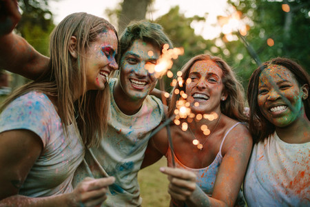 Group of friends burning fire sparkles while playing holi
