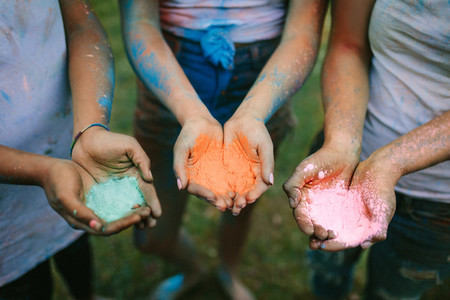 Close up of hands of three women holding holi colours