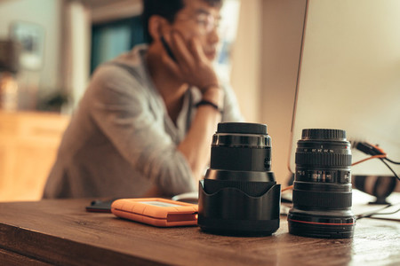 Photographer editing photos with lenses on table