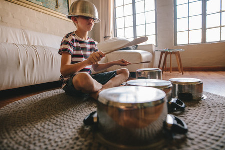 Boy playing drums on kitchenware at home