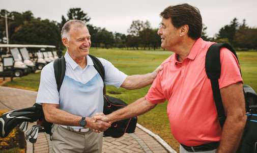 Mature golfers meeting at the golf course and shaking hands