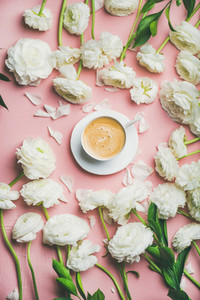 Flat lay of cup of coffee surrounded with white ranunculus flowers