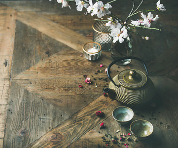 Asian golden iron teapot  cups  candles and almond blossom flowers