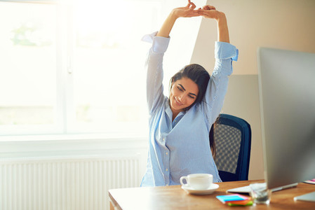 Woman stretching in front of desk at home