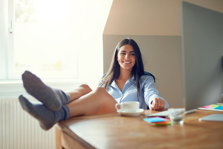 Happy female adult in socks with feet on desk