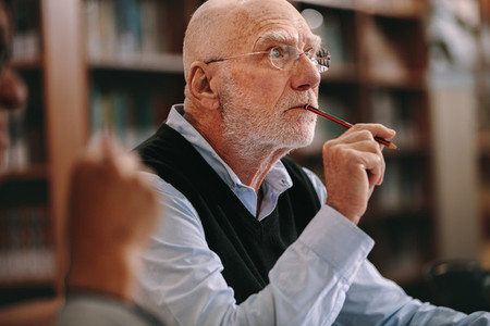 Senior man thinking deeply sitting in classroom