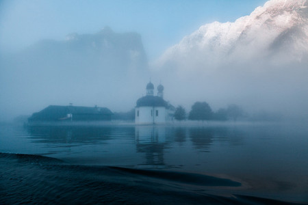 Views of St Bartholomews Church among fog in the autumn from konigsee lake