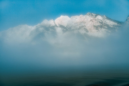 views of forest in the mountain among fog in border of the lake