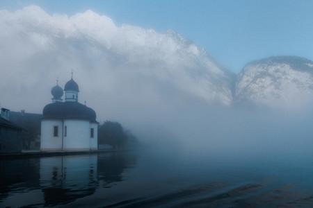 Views of St Bartholomews Church among fog in the autumn from konigsee lake