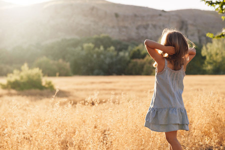 Young blonde girl playing with sunlight in the fields sunset