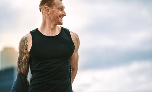 Close up of a smiling fitness man looking away