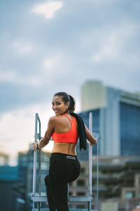 Smiling fitness woman standing on rooftop staircase