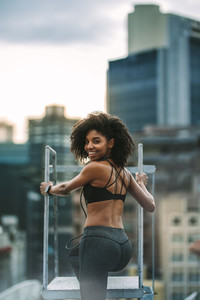 Fitness woman standing on rooftop looking back