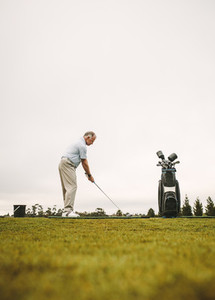 Senior golfer practicing at golf course driving range
