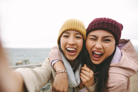 Two asian women friends having fun standing outdoors