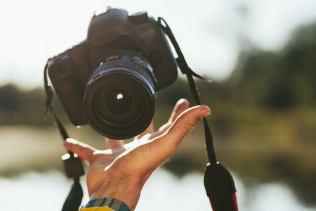 Close up of a hand of man tossing up a dslr camera