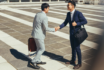 Two businessmen shaking hands outdoors in the city