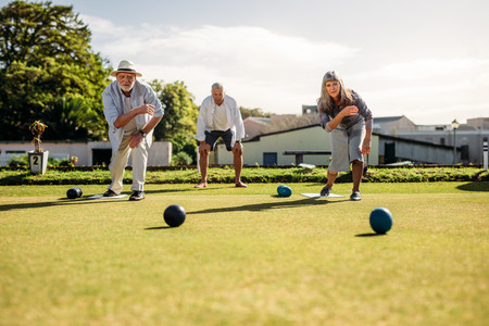 Senior man and woman playing boules in a lawn