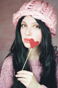 Romantic woman wearing pink clothes and holding a red heart