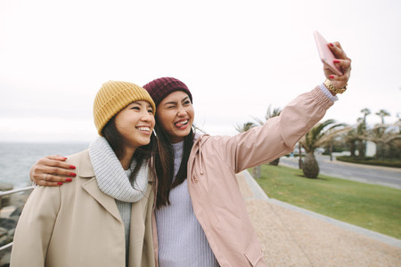 Happy girl friends taking a selfie standing outdoors
