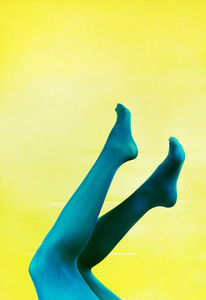 Pop art piece of young woman legs in tights against a yellow bac