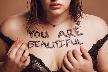 Plus size woman with you are beautiful written on her body