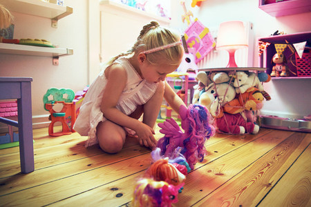Girl placing toys in line on floor