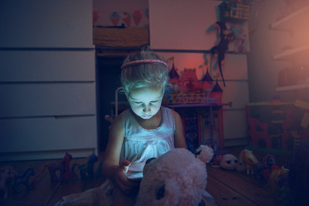 Child with tablet and bear at night