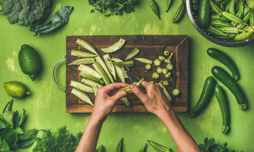 Flat lay of healthy green vegan cooking ingredients over green background