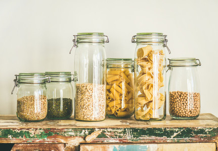 Uncooked cereals grains beans and pasta in jars on table