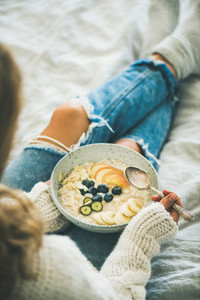 Woman in shabby jeans and sweater eating vegan breakfast
