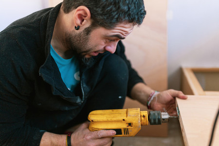Young man with a drill restoring his old caravan