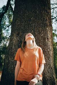 Young blonde woman supported on a tree with black jeans