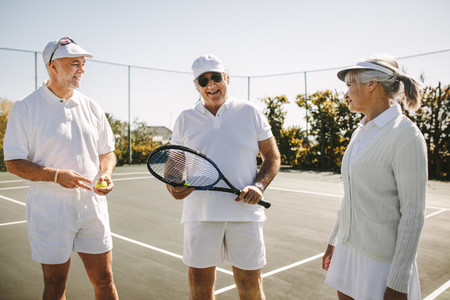 Senior men and a woman playing tennis