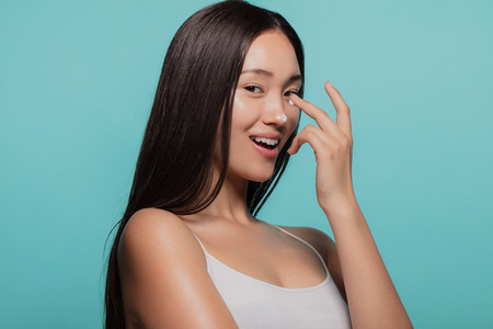 Woman applies moisturizer on her face