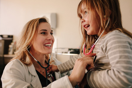 Friendly pediatrician playing with her girl patient at clinic