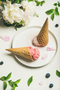 Ice cream scoops and peony flowers over white background