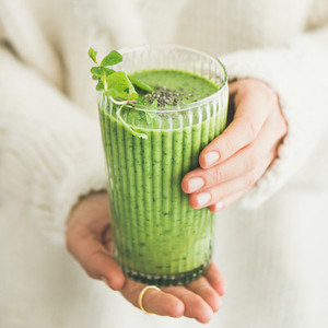 Matcha smoothie with chia seeds in female hands square crop