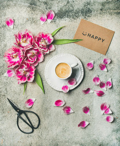 Cup of coffee surrounded with pink tulip flowers