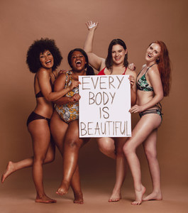 Cheerful female group with every body is beautiful signboard