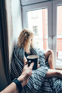 girl sitting on a window in a blanket